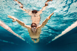 A man swimming in a pool, following a dedicated lane for laps or training, with focused and rhythmic strokes.