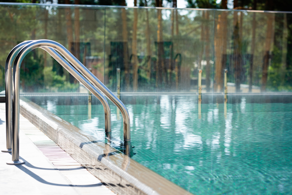 Handrails along the edge of a pool with a modern fiberglass wall, providing support and safety for swimmers while maintaining a contemporary and clean design.