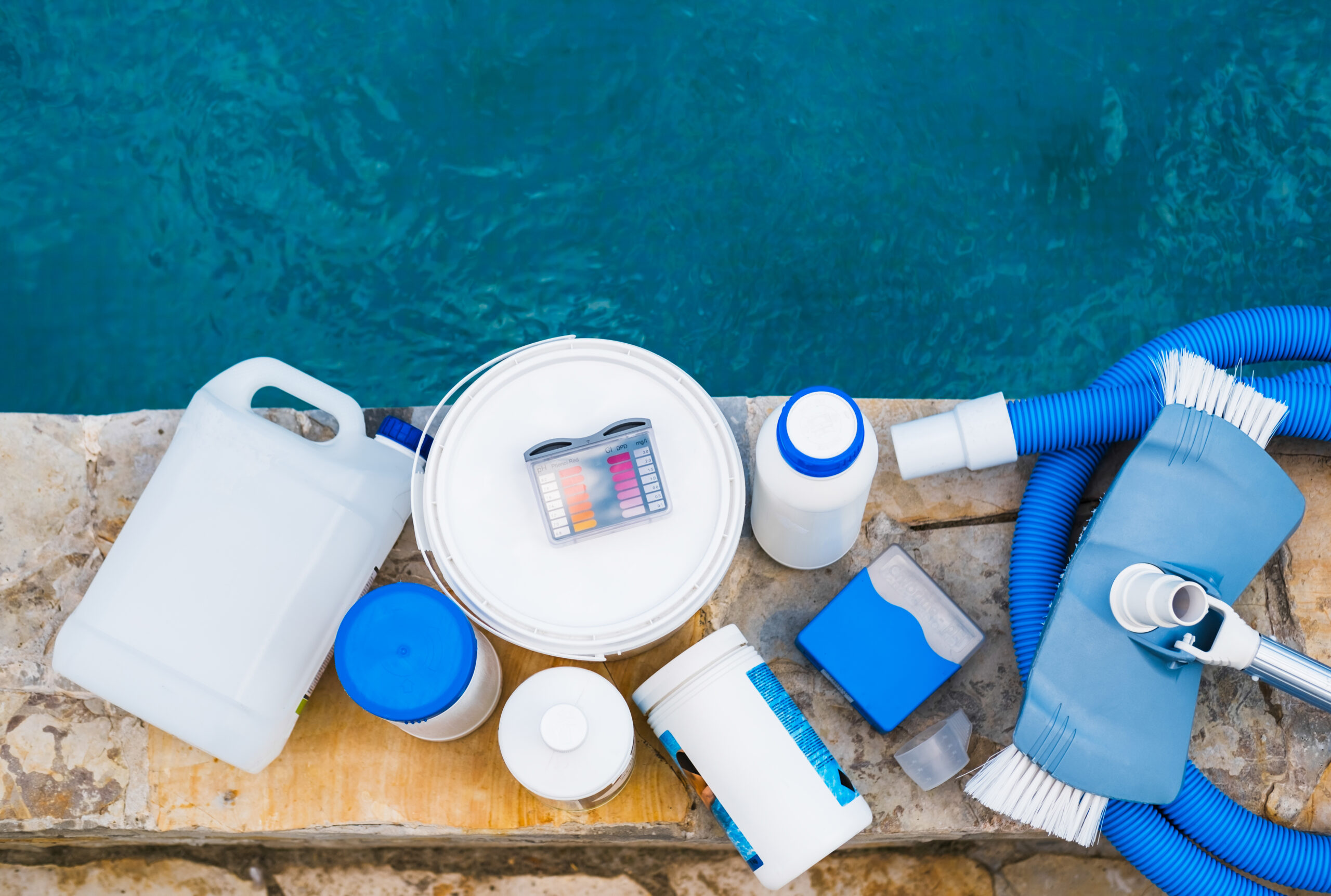 Various pool cleaning materials including a pool skimmer, vacuum head, pool brush, and chemical test kit