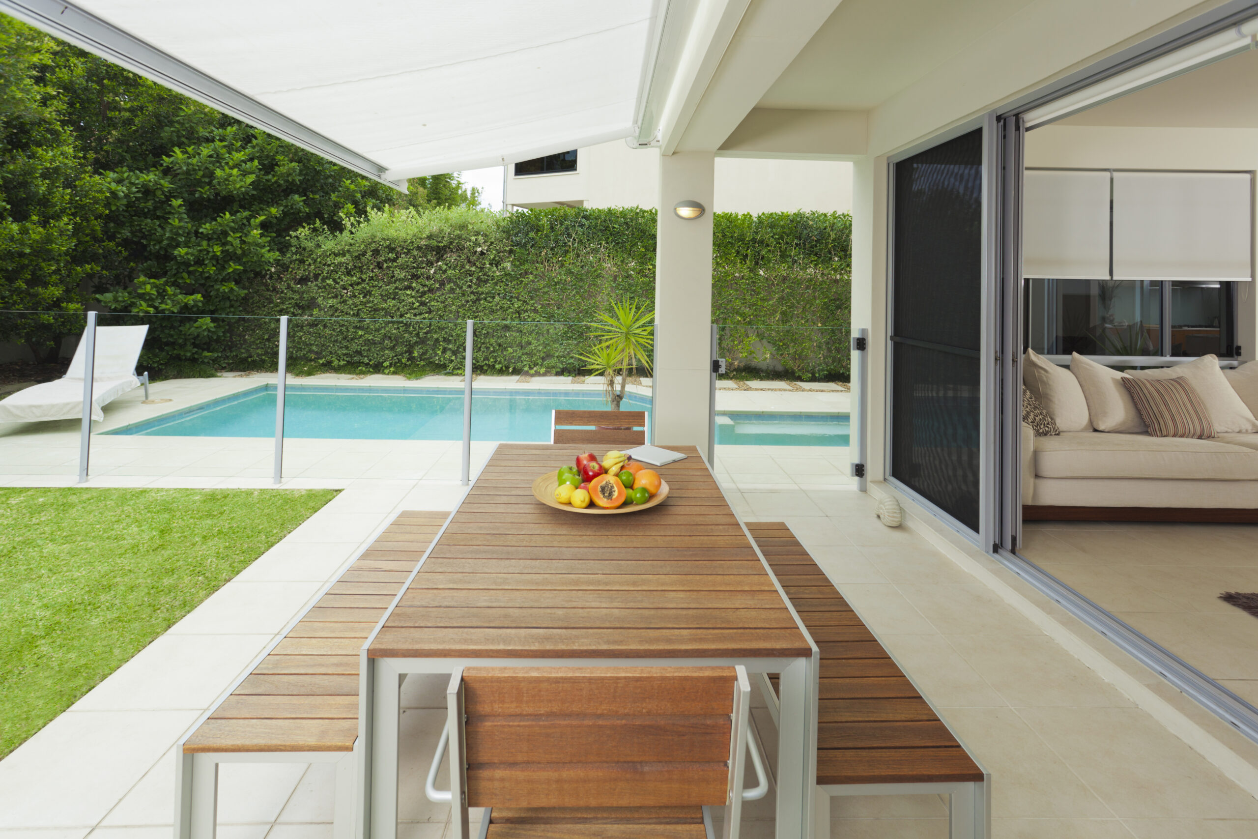 Modern suburban backyard and living room with table setting and swimming pool