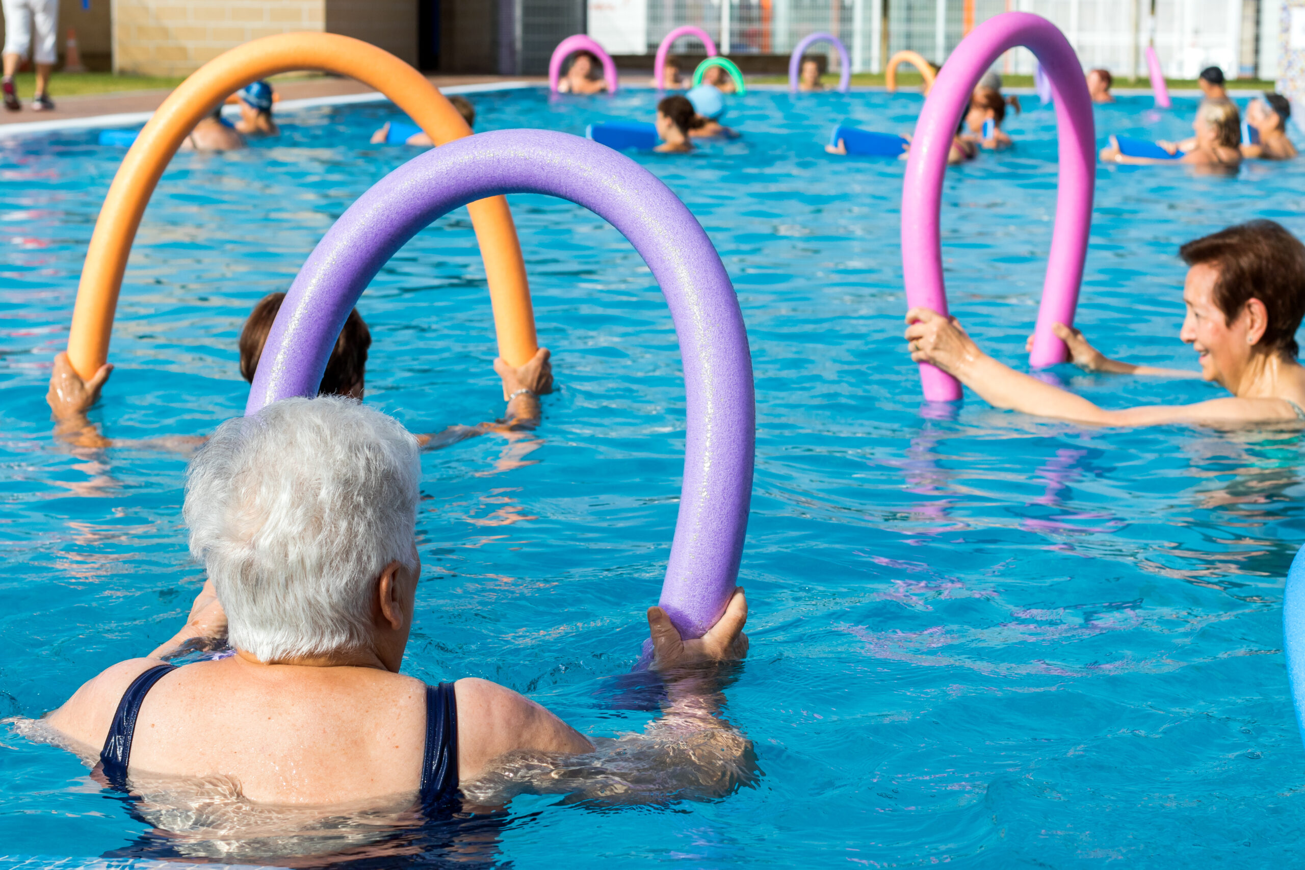 Elderly individuals engaged in various activities by the pool, demonstrating a vibrant and active lifestyle for seniors.
