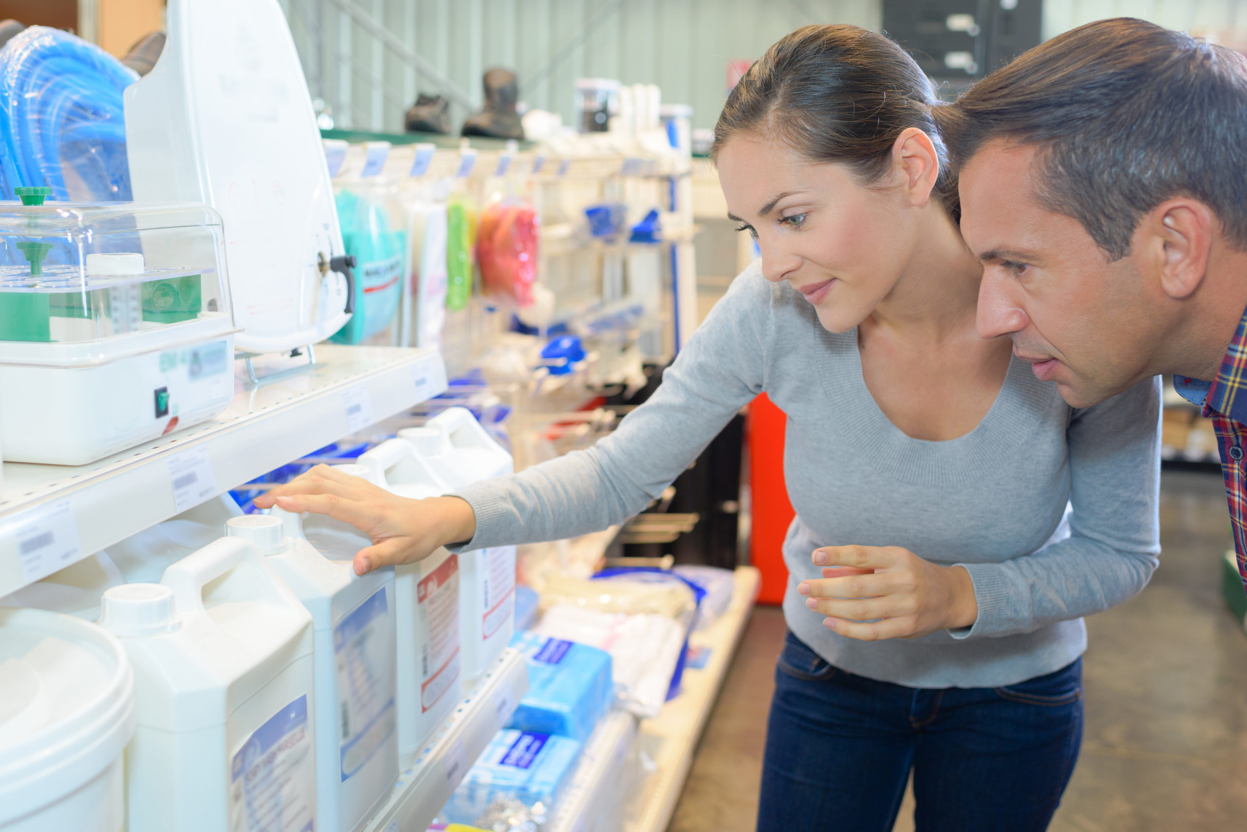 A man and a woman shopping at a store, browsing pool filtration equipment, searching for the right products to maintain their swimming pool.