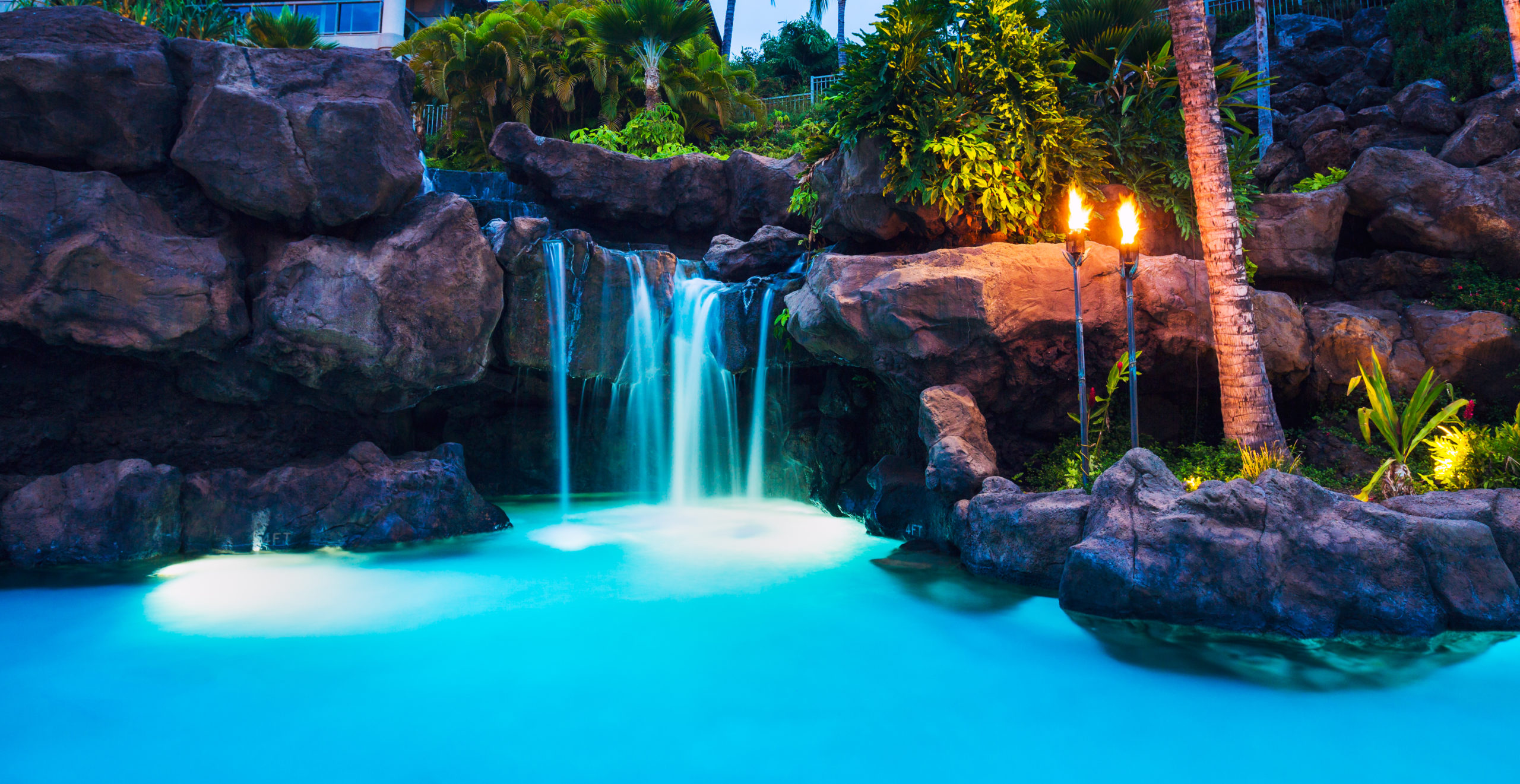 A pool with cascading waterfalls and vibrant lighting, creating a visually stunning and serene aquatic ambiance.