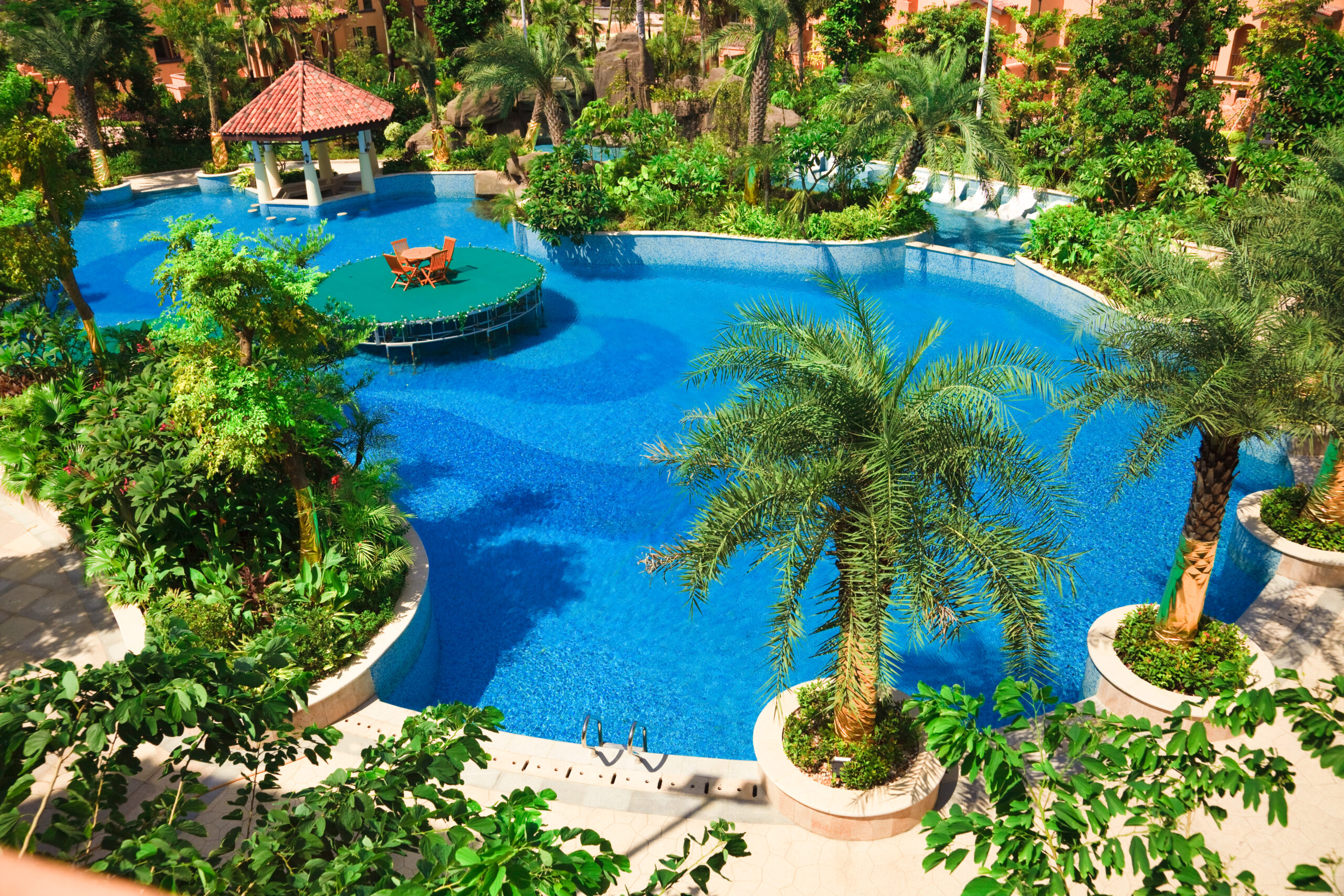 An above shot of a freeform-shaped pool surrounded by trees, showcasing a natural and organic design that harmonizes with the lush greenery.