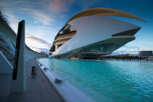 A swimming pool located near a large building, offering a juxtaposition of aquatic and architectural elements.