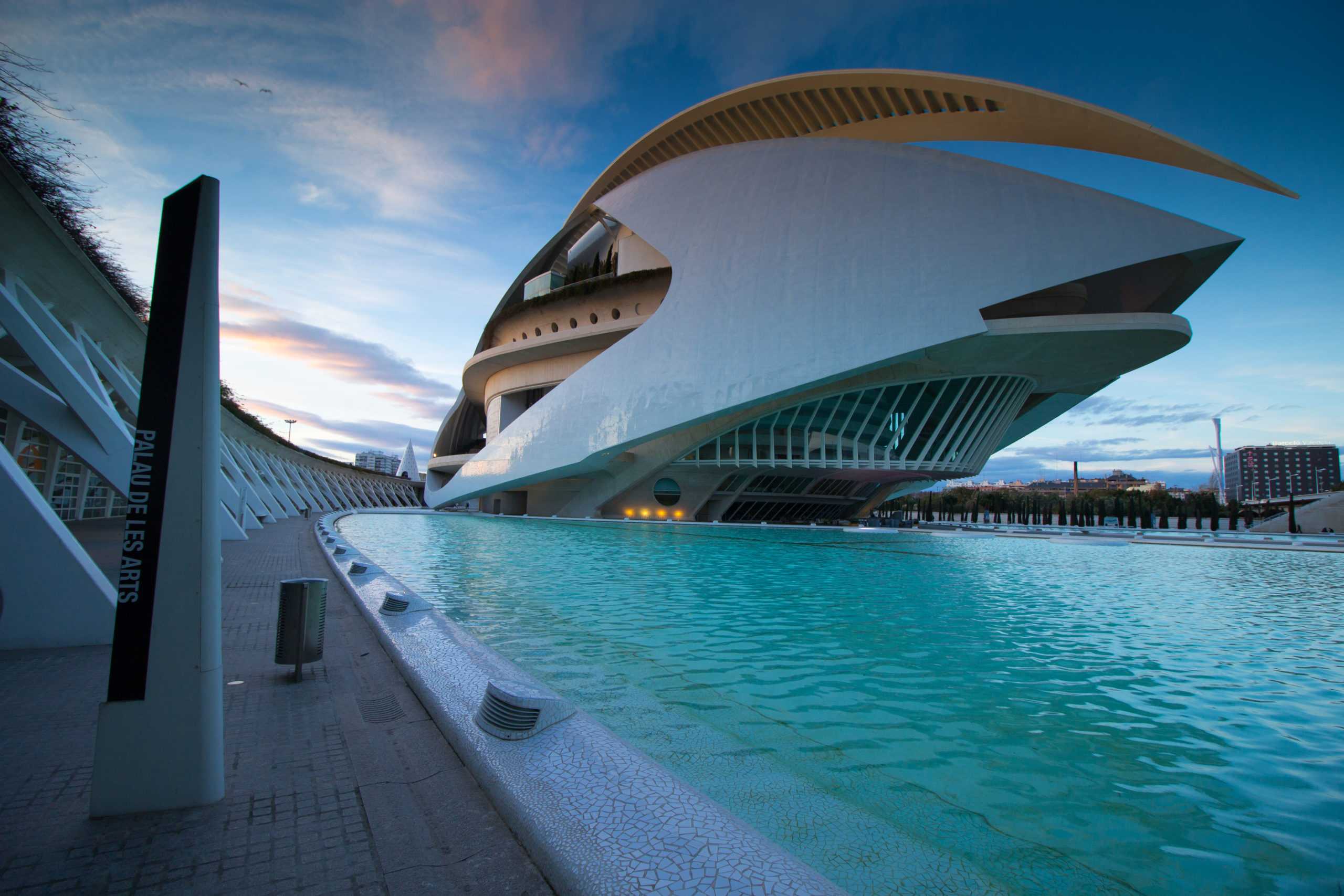 A swimming pool located near a large building, offering a juxtaposition of aquatic and architectural elements.