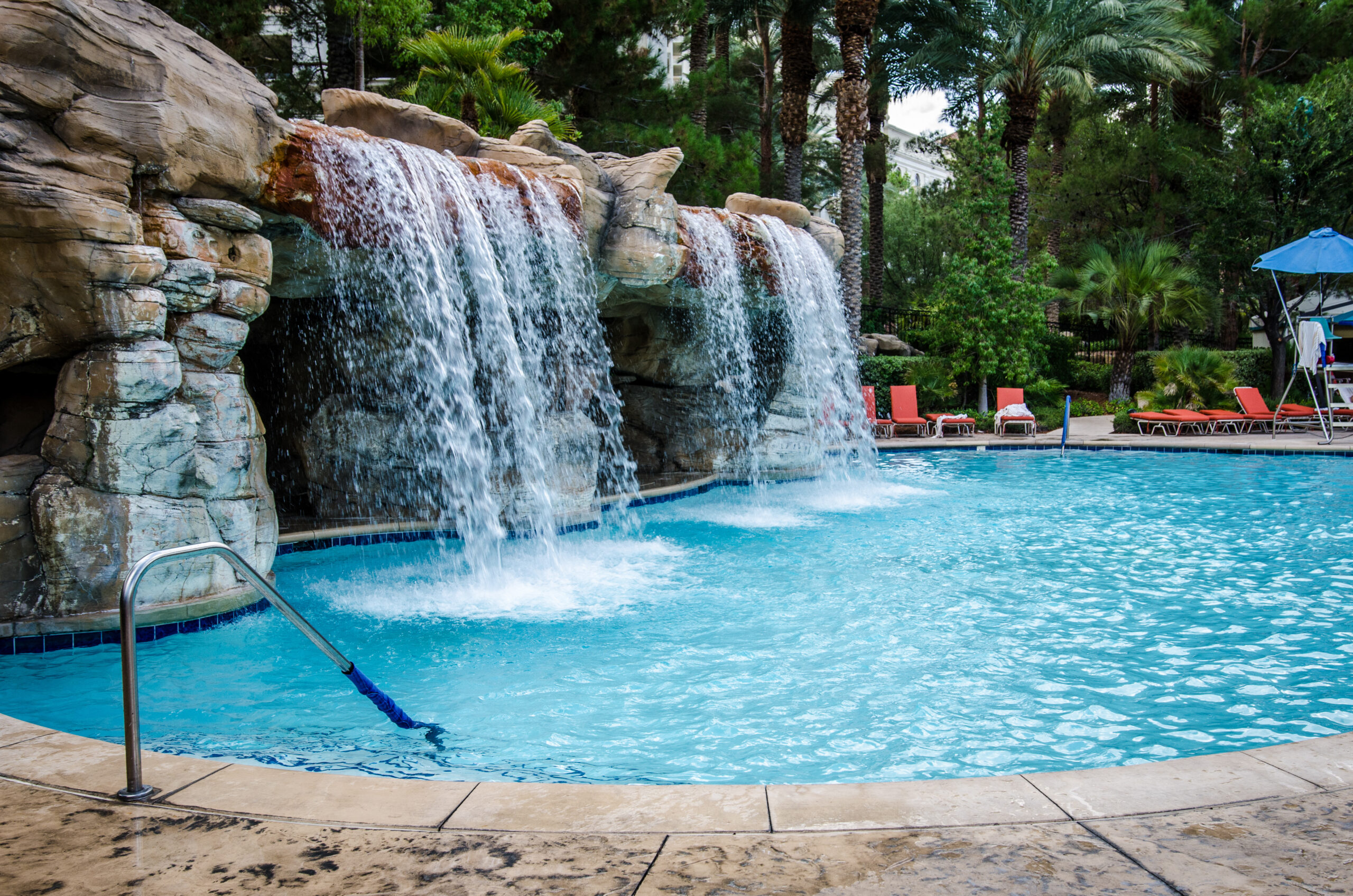 A pool with cascading waterfalls, providing both a visually stunning feature and a soothing auditory backdrop, enhancing the overall ambiance of the swimming area.