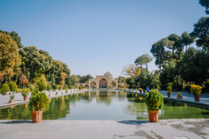 A long pool in front of the ancient Chehel Sotoun palace surrounded by trees in the garden. Isfahan, Iran.