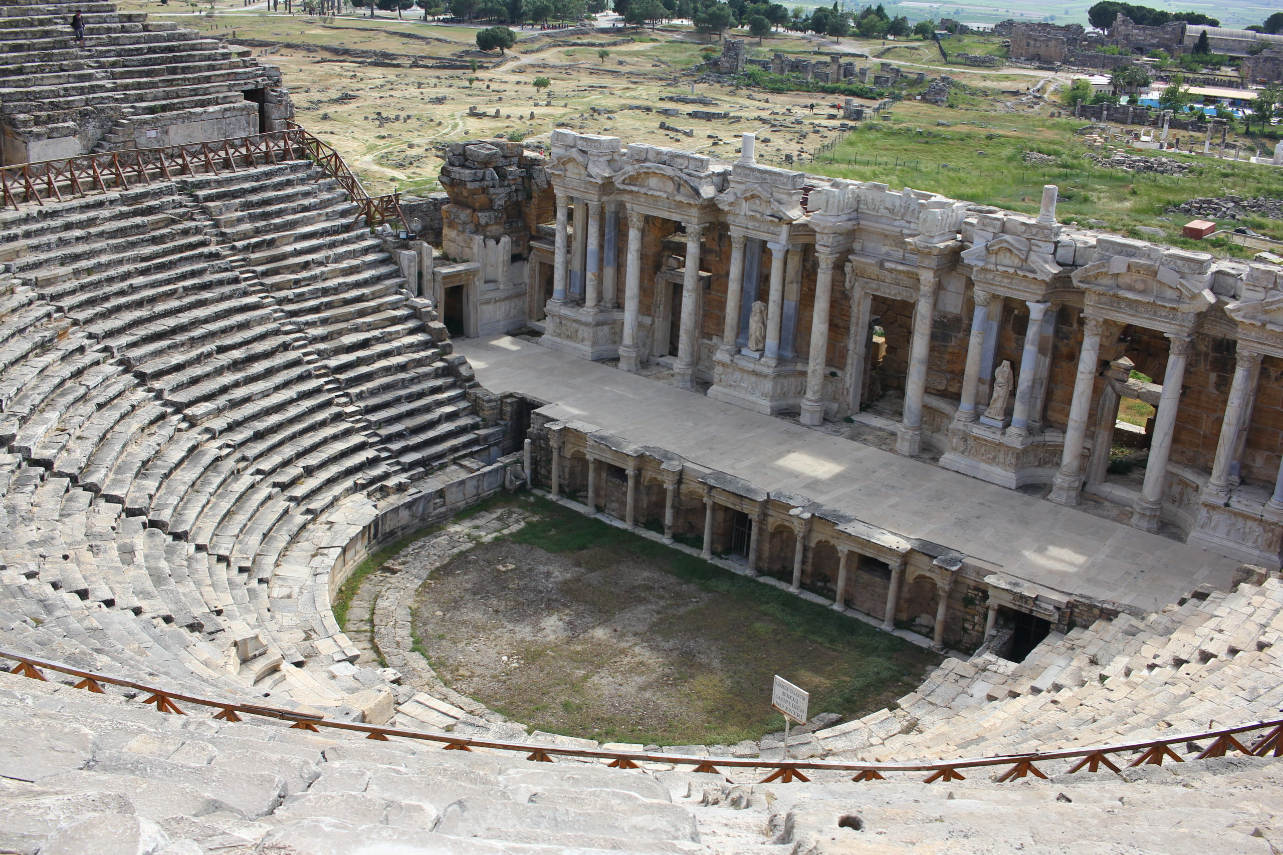 An empty Roman-style pool featuring exquisite mosaic tile work, classical sculptures, and intricate architectural details, evoking the grandeur of ancient Roman baths.