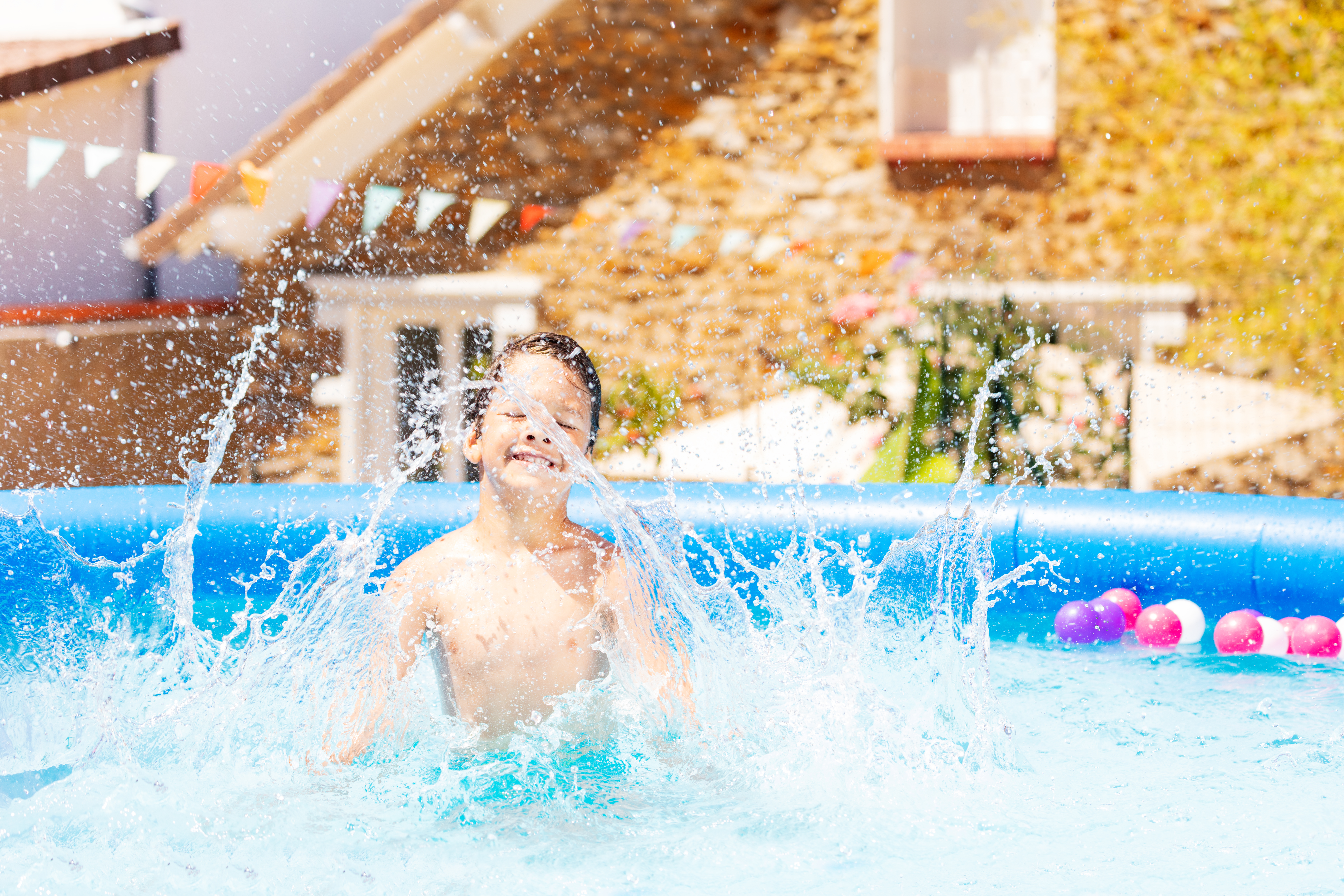 A child joyfully splashing in a pool, creating ripples in the water as they play and have fun in the refreshing pool.