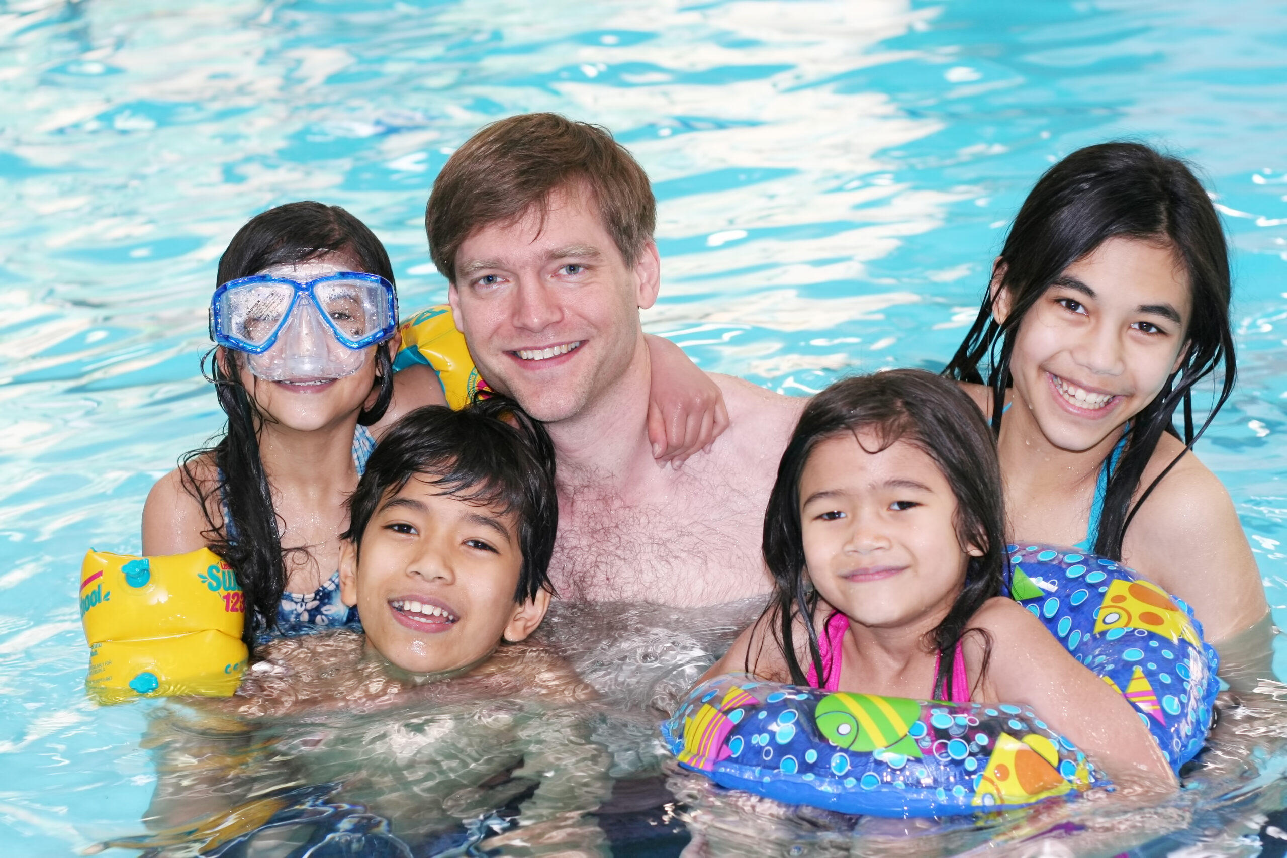 A family enjoying time together by the pool, featuring parents and children