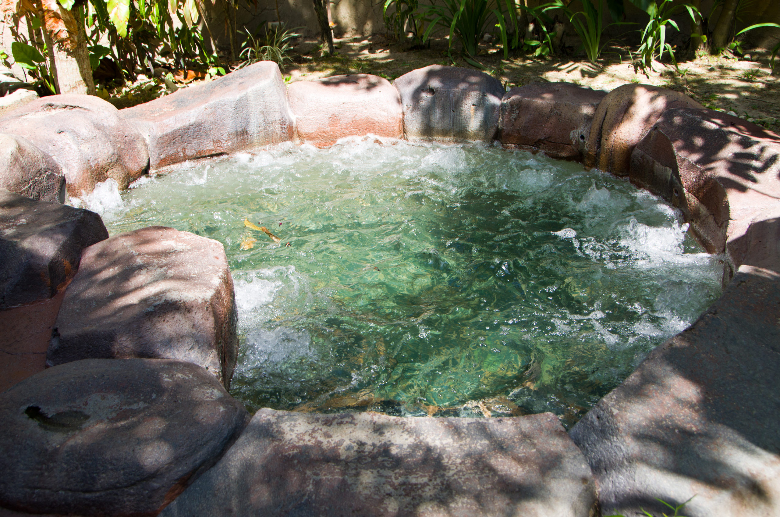 A natural stone pool crafted from rustic stones and boulders, seamlessly blending into its natural surroundings, providing a serene and organic swimming experience.