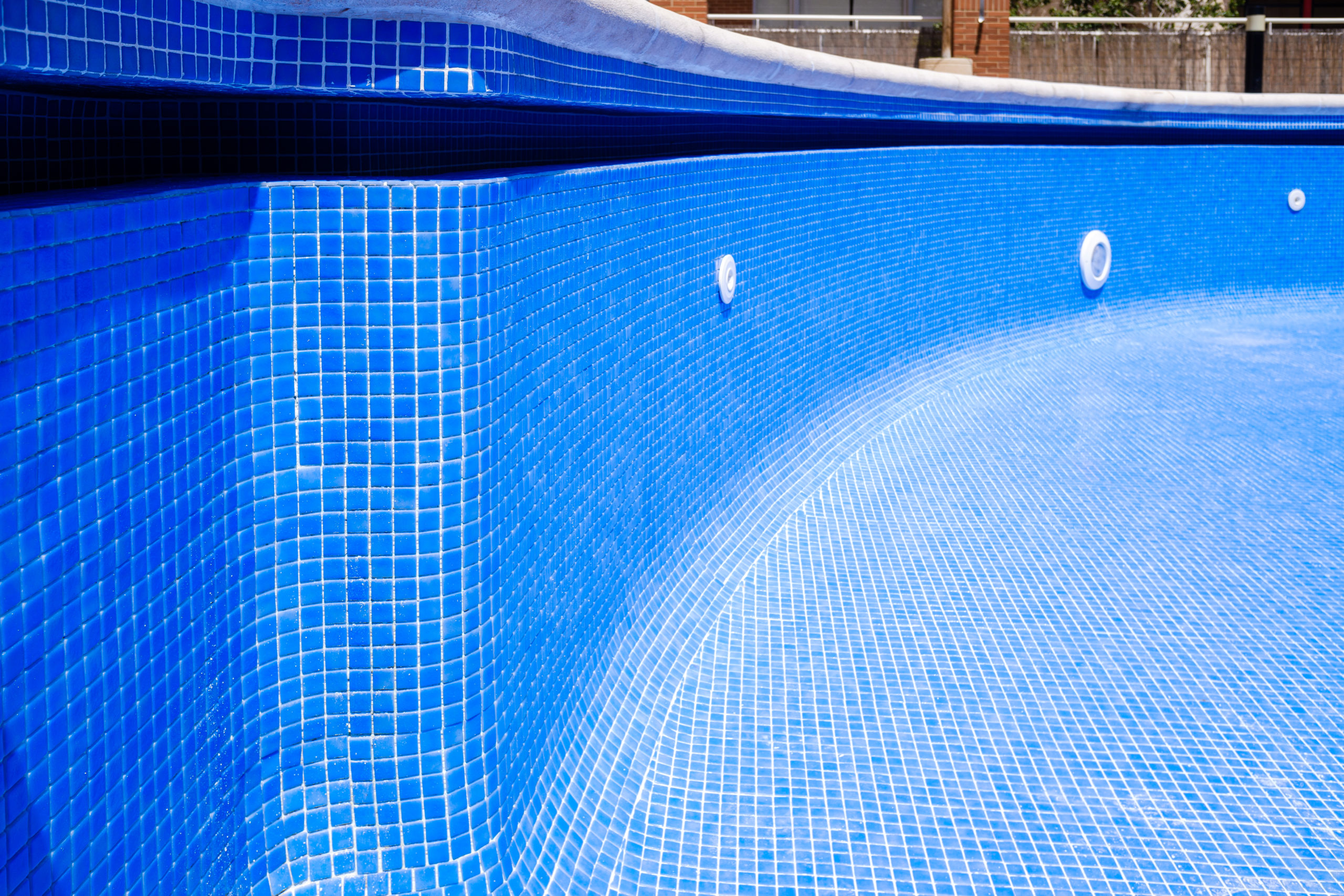 An empty pool with tiled surfaces, showcasing the clean and polished appearance of the pool's interior when not filled with water