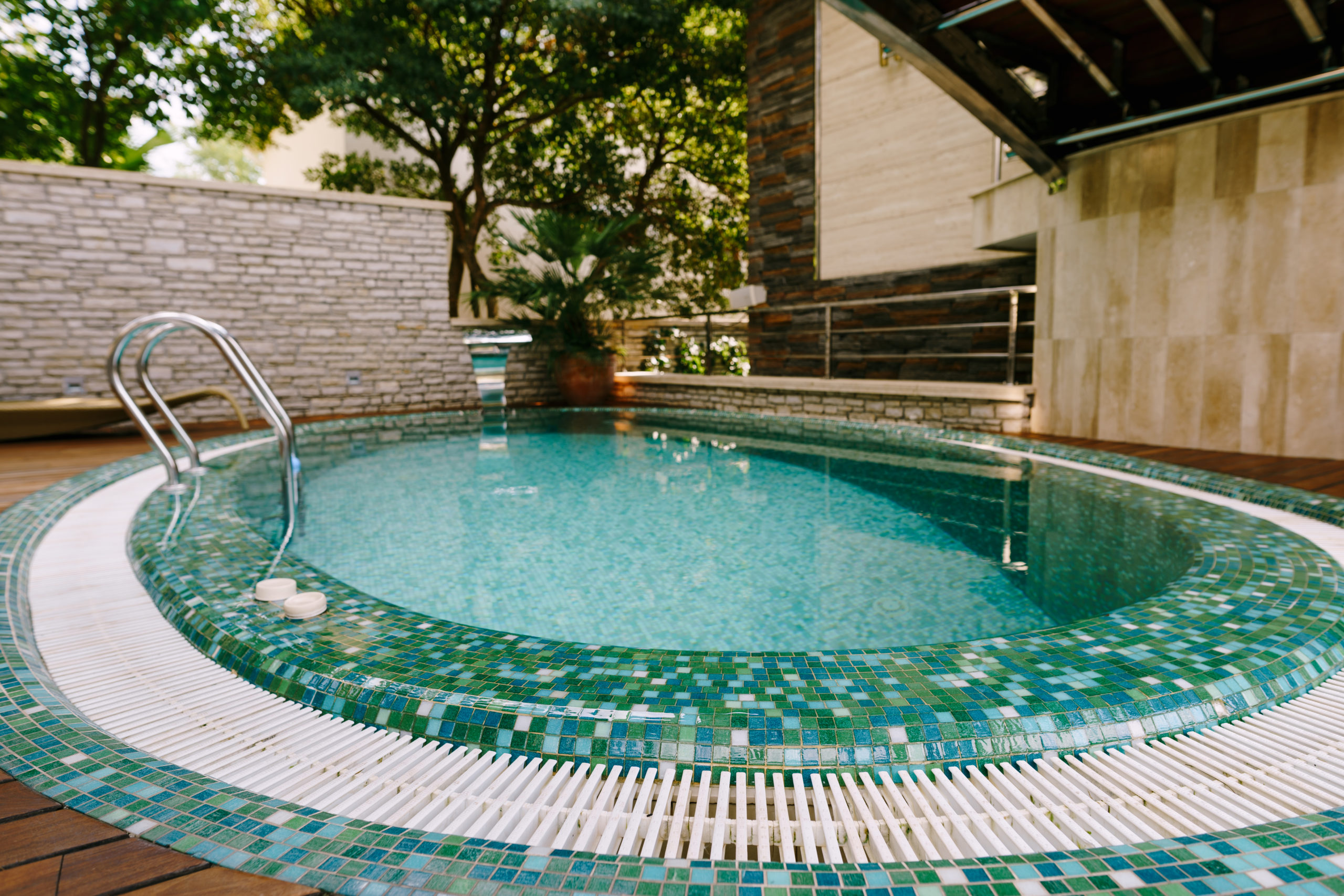 A round pool with green tiles, showcasing a visually appealing and vibrant pool design.