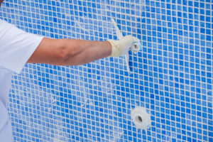 Pool renovation work. A worker lays the tiles and covers the sea