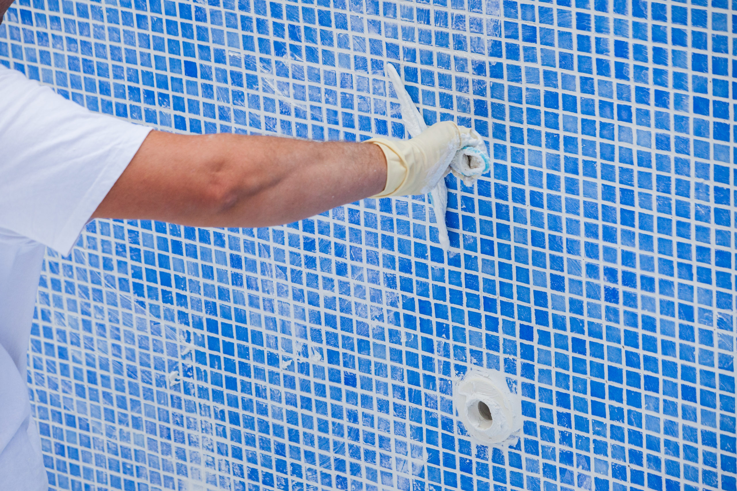 Pool renovation work. A worker lays the tiles and covers the sea