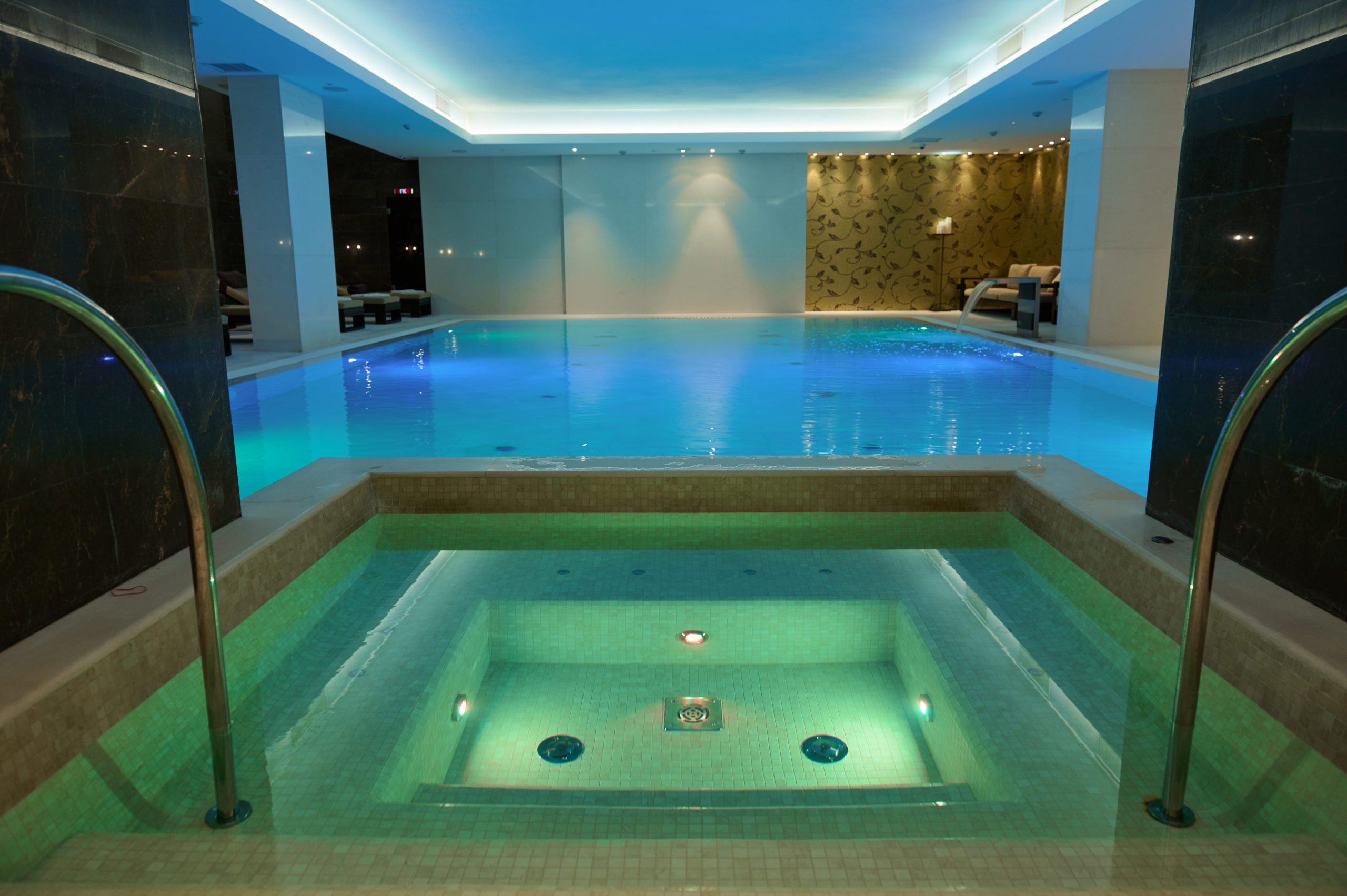 A pool illuminated by underwater lighting, creating a captivating and colorful ambiance with vibrant lights shining from beneath the water's surface.