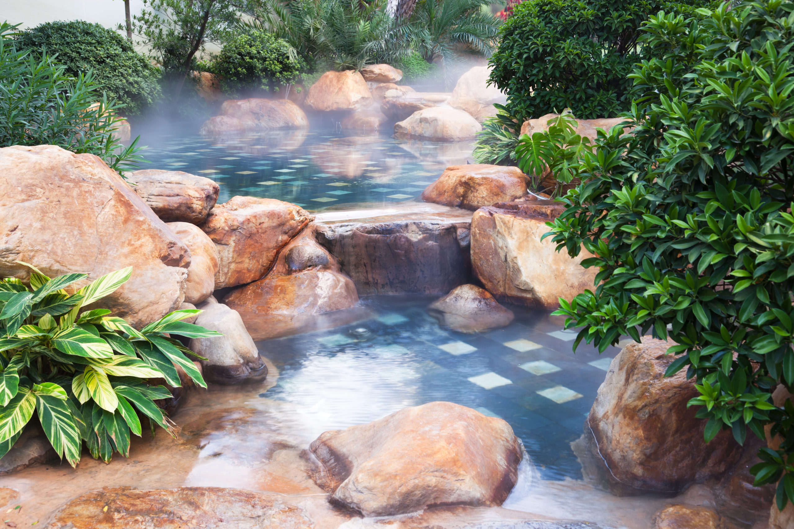 An overflowing pool with a cascading water feature, surrounded by natural rock formations, offering a picturesque and harmonious blend of water and earth elements.