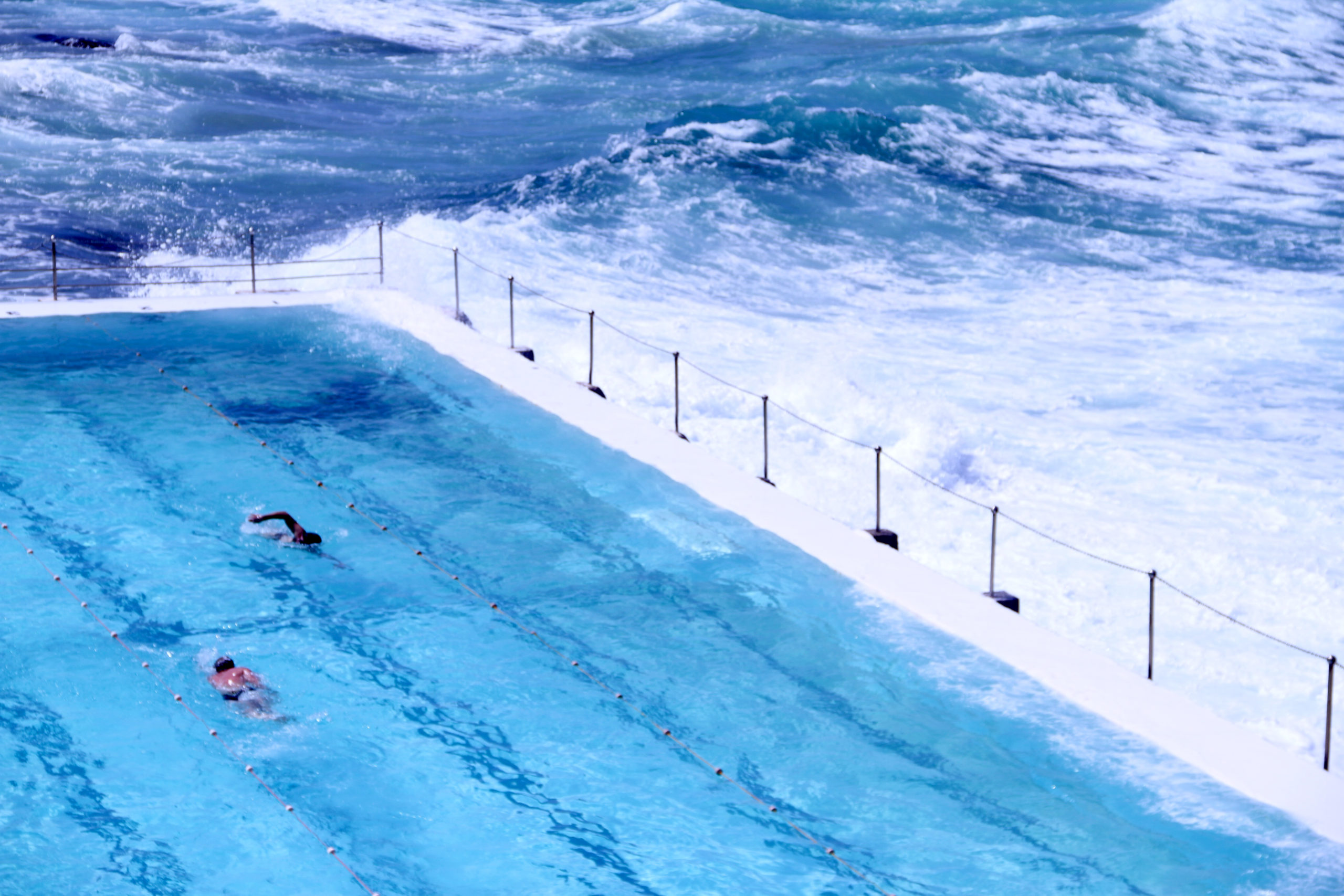 The Icebergs Pool in Sydney, Australia, a stunning oceanside swimming pool carved into the rocky coastline, offering breathtaking views of the ocean and Bondi Beach.