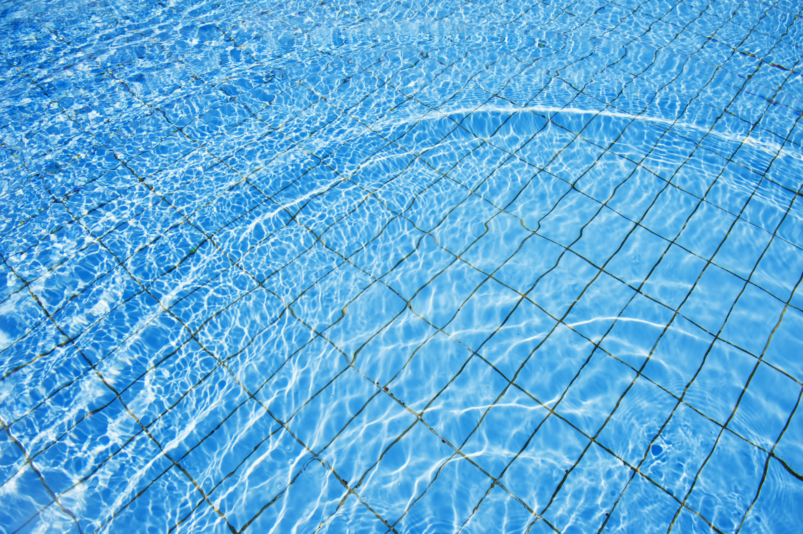 Crystal clear water in the swimming pool with small waves