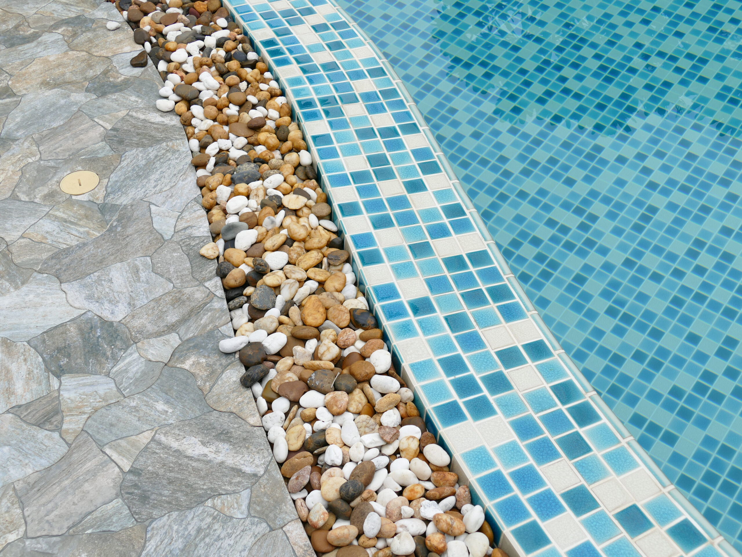 Natural elements incorporated into pool design, such as rocks and stones at the poolside, creating an organic and harmonious blend of water and earth aesthetics.