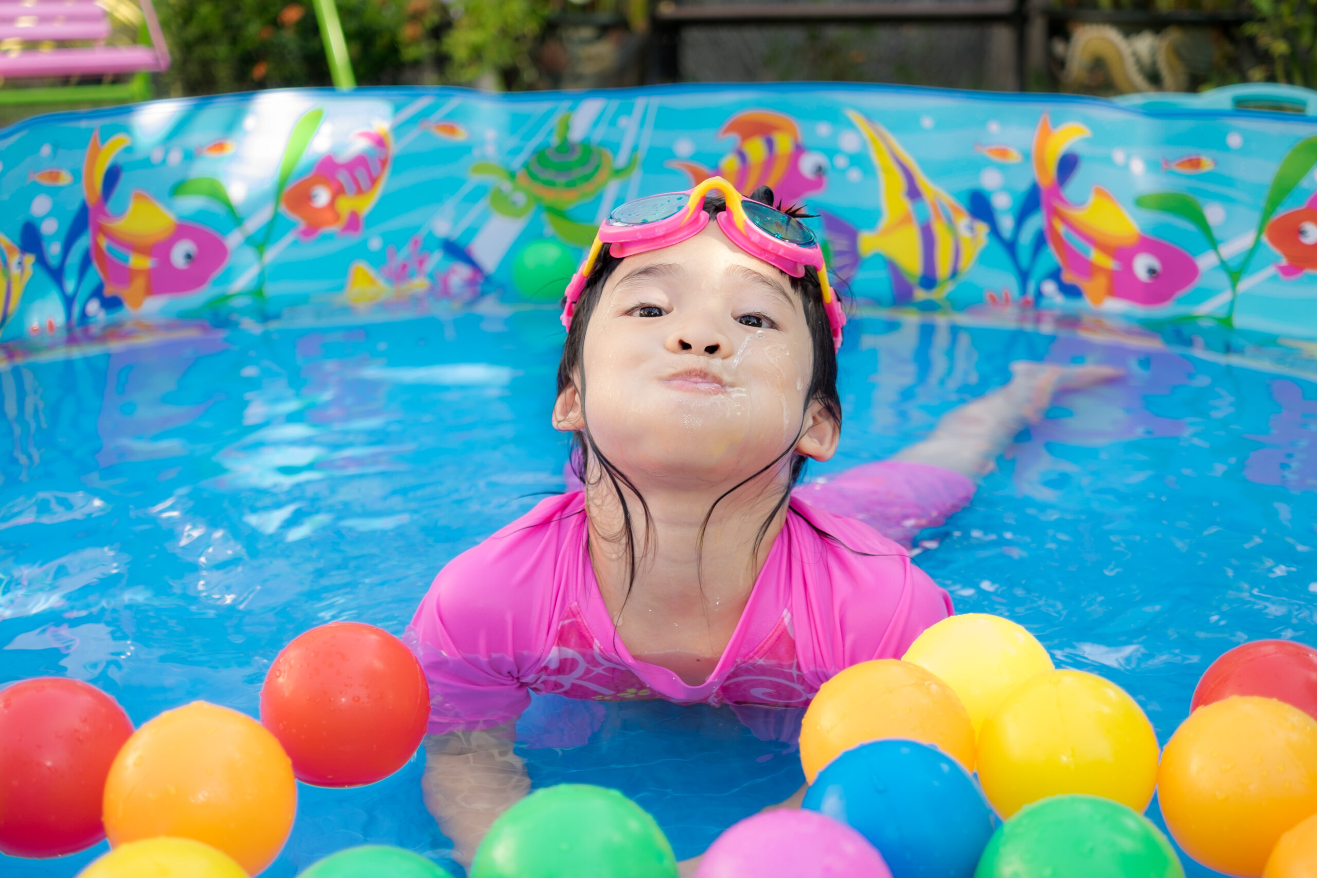 A child gleefully enjoying a pool filled with colorful balls, experiencing a playful and vibrant aquatic activity.