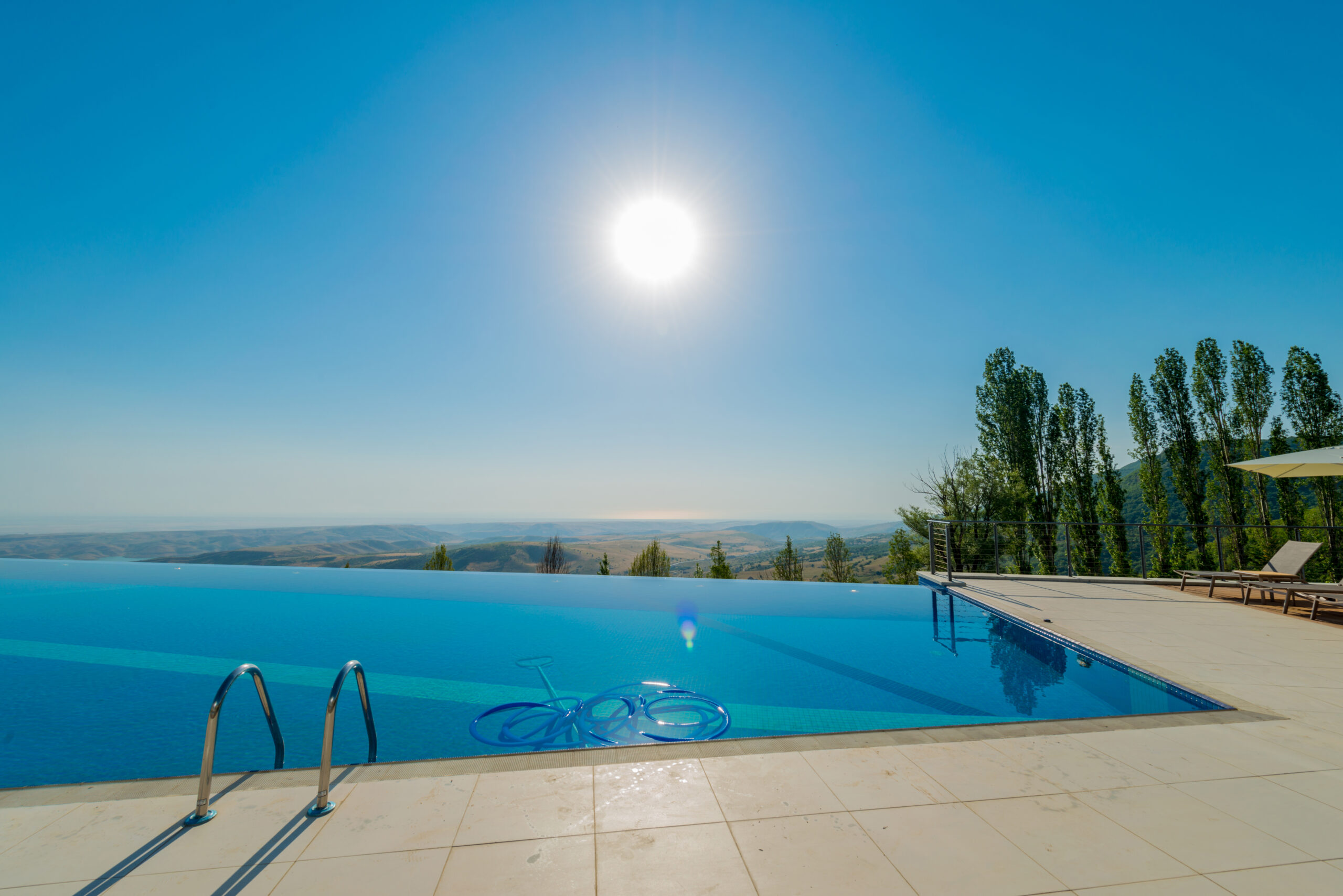 Construction of an infinity pool under sunlight, showcasing the initial stages of creating a visually captivating pool that appears to blend seamlessly with the surrounding landscape.