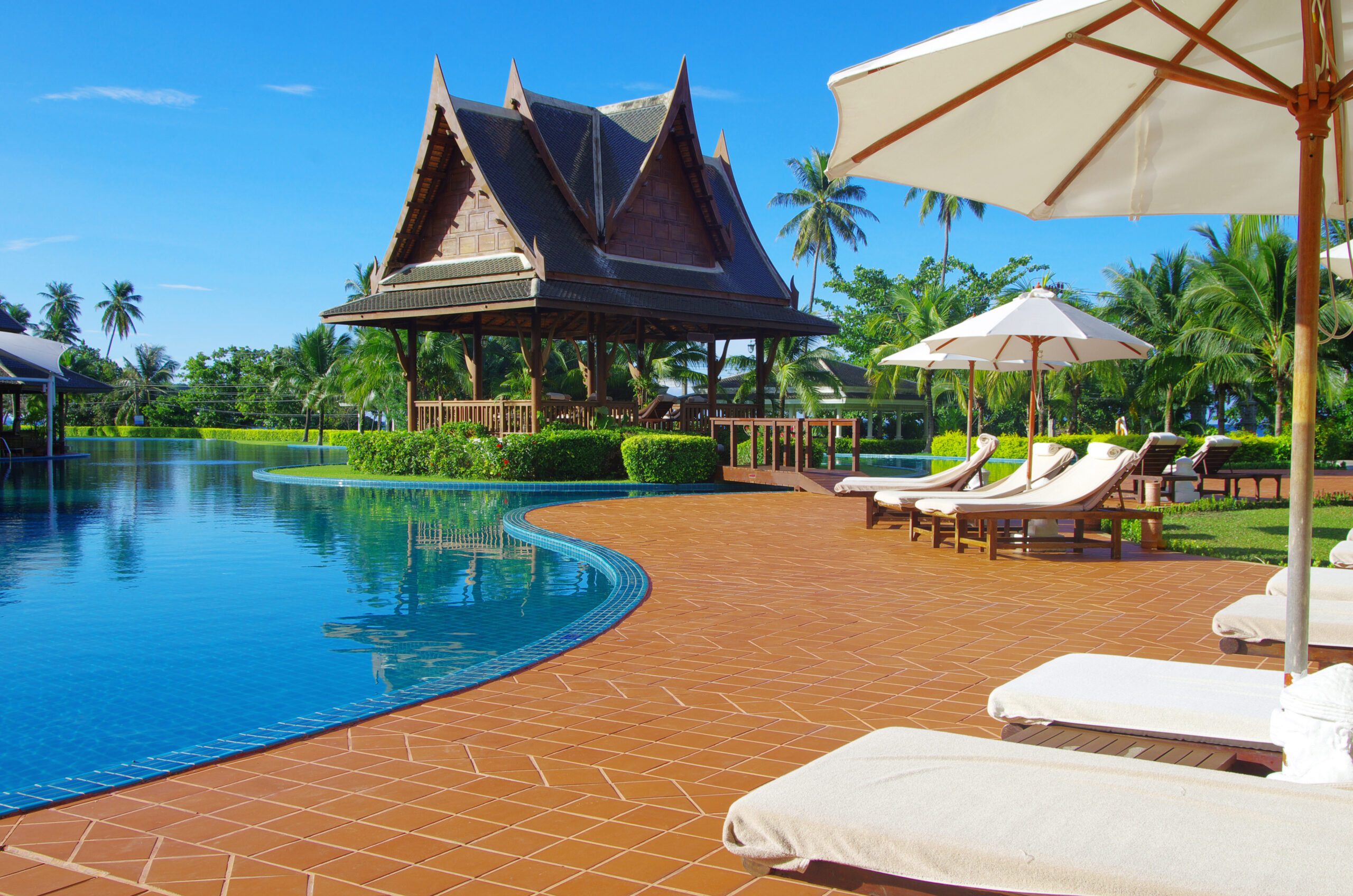 A pool with a small house or poolside cabana and chairs arranged by the water's edge